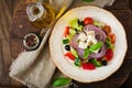 Greek salad with fresh tomato, cucumber, red onion, basil, lettuce, feta cheese, black olives and a Italian herbs on plate. Royalty Free Stock Photo