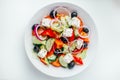 Greek salad with fresh tomato, cucumber, red onion, basil, lettuce, feta cheese, black olives and Italian herbs. Top view Royalty Free Stock Photo