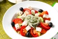 Greek salad, fresh vegetable salad, cheese and black olives in a white plate, top view