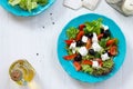 Greek salad with fresh vegetables, feta cheese and black olives in a blue plate on white wooden table. Royalty Free Stock Photo