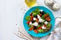 Greek salad with fresh vegetables, feta cheese and black olives in a blue plate on white wooden table. Royalty Free Stock Photo