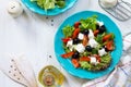 Greek salad with fresh vegetables, feta cheese and black olives in a blue plate on white wooden table. Royalty Free Stock Photo