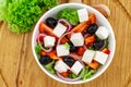 Greek salad with fresh vegetables, feta cheese and black olives on a wooden background. Top view Royalty Free Stock Photo