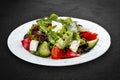Greek salad with fresh vegetables and feta cheese. Isolated on a black background Royalty Free Stock Photo