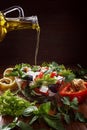 Greek salad with olive oil pouring from a bottle. Royalty Free Stock Photo