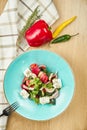 Greek salad with olives, tomatoes, feta cheese, onions in blue bowl on wooden background. Close up. Selective focus Royalty Free Stock Photo