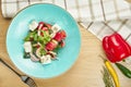 Greek salad with olives, tomatoes, feta cheese, onions in blue bowl on wooden background. Close up. Selective focus Royalty Free Stock Photo