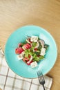 Greek salad with olives, tomatoes, feta cheese, onions in blue bowl on wooden background. Close up. Selective focus Royalty Free Stock Photo