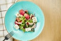 Greek salad with olives, tomatoes, feta cheese, onions in blue bowl on wooden background. Close up. Selective focus Royalty Free Stock Photo