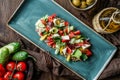 Greek salad of organic vegetables with tomatoes, cucumbers, olives, feta cheese in plate over brown wooden background Royalty Free Stock Photo