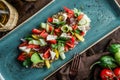 Greek salad of organic vegetables with tomatoes, cucumbers, olives, feta cheese in plate over brown wooden background. Royalty Free Stock Photo