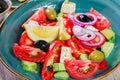 Greek salad of organic vegetables with tomatoes, cucumbers, red onion, olives, feta cheese and glass of wine on wooden background Royalty Free Stock Photo