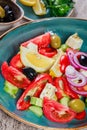 Greek salad of organic vegetables with tomatoes, cucumbers, red onion, olives, feta cheese and glass of wine on wooden background Royalty Free Stock Photo