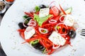 Greek salad of organic vegetables with tomatoes, cucumbers, red onion, olives, feta cheese and sweet pepper on wooden background. Royalty Free Stock Photo