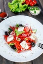 Greek salad of organic vegetables with tomatoes, cucumbers, red onion, olives, feta cheese and sweet pepper on wooden background. Royalty Free Stock Photo