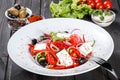 Greek salad of organic vegetables with tomatoes, cucumbers, red onion, olives, feta cheese and sweet pepper on wooden background. Royalty Free Stock Photo