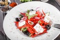 Greek salad of organic vegetables with tomatoes, cucumbers, red onion, olives, feta cheese and sweet pepper on wooden background Royalty Free Stock Photo