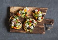Greek salad style bruschetta on a wooden cutting board, on dark background, top view. Royalty Free Stock Photo