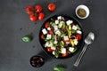 Greek salad - vegetable salad of fresh tomatoes, bell peppers, feta cheese and olives in a black plate on a dark background Royalty Free Stock Photo