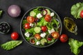 Greek salad. Vegetable salad from tomato, cucumber, feta cheese and olives on black table. Top view. Vegetarian food Royalty Free Stock Photo