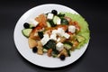 Greek salad on a white plate on a black background. Can be used as a photo for restaurant menus, bistro. European, Mediterranean c Royalty Free Stock Photo