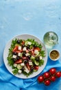 Greek salad on white plate on bright blue table, top view, copy space Royalty Free Stock Photo