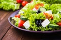 Greek salad (lettuce, tomatoes, feta cheese, cucumbers, black olives) on dark wooden background close up Royalty Free Stock Photo