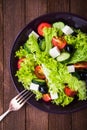 Greek salad (lettuce, tomatoes, feta cheese, cucumbers, black olives) on dark wooden background top view Royalty Free Stock Photo