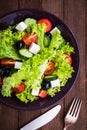 Greek salad (lettuce, tomatoes, feta cheese, cucumbers, black olives) on dark wooden background top view Royalty Free Stock Photo