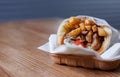 Greek souvlaki meat wrapped in pita bread with fries and white tzatziki sauce and served on disposable paper plate for take away Royalty Free Stock Photo