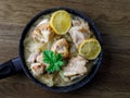 Greek stewed chicken with lemons, onions and scented leaved pelargonium leaves close-up on a iron pan on a table