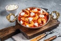 Greek traditional oven backed prawns shrimp saganaki with feta, tomato, paprika and thyme. Gray background. Top view