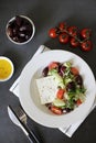 Greek vegetable salad with cheese in a white plate on a black background. Royalty Free Stock Photo