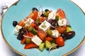 Greek vegetable salad with tomatoes, olives, feta on a blue plate