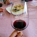 Greek wine tasting. A glass in hand with a bit of red wine. In the background, bread with olive oil