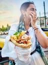 Greek woman eating a Gyros in a street of Athens.