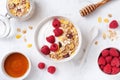 Greek yogurt in bowl with raspberries, honey and muesli on white stone table top view. Healthy diet breakfast