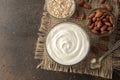 Greek yogurt in a glass bowl next to a spoon, oatmeal and almonds on a dark background. healthy food. natural yoghurt. breakfast.