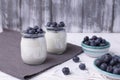 Greek yogurt in a glass jar and fresh blueberries on a rustic white table. Healthy food concept. Selective focus Royalty Free Stock Photo