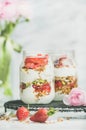 Greek yogurt, granola, fresh strawberry breakfast jars, pink raninkulus flowers Royalty Free Stock Photo