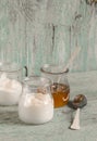 Greek yogurt and honey in a glass jar on blue wooden surface