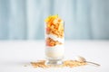 greek yogurt layered with peach slices and crunchy cereal in a tall glass