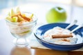 greek yogurt parfait with a cinnamon stick and apple slices in a white bowl