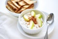 greek yogurt parfait with a cinnamon stick and apple slices in a white bowl