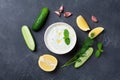 Greek yogurt sauce tzatziki with cucumber, dill, lemon, mint and garlic on stone table top view.