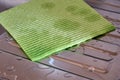 A green absorbent napkin for the kitchen, lying on a wet stainless steel sink. Close-up