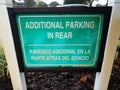 Green additional parking in rear sign in English and Spanish