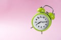 Green alarm clock with two bells showing ten minutes past seven on the pink background Royalty Free Stock Photo