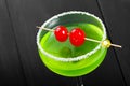 Green alcoholic cocktail with cherry in a glass on dark background. Royalty Free Stock Photo