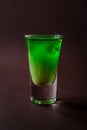 Green alcoholic shot glass with absent, irish cream, liquor on e